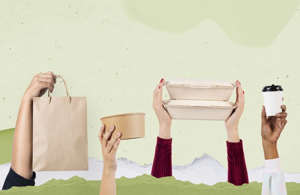 Four hands hold up eco-friendly items: a paper bag, a round container, stackable food trays, and a disposable coffee cup against a green and light background—an inspiring scene for anyone learning how to choose the right food packaging boxes.