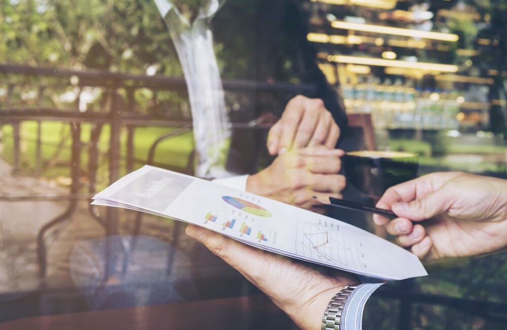 Two people in business attire reviewing a report with bar and line charts during a consultation for Singapore audit services for growing businesses.